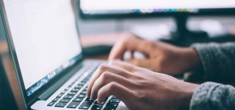 Hands typing on a laptop.